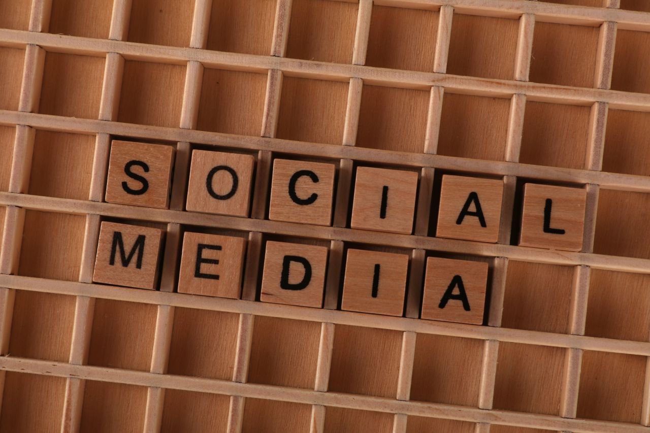 Close-up of wooden letter blocks spelling Social Media on a wooden grid.